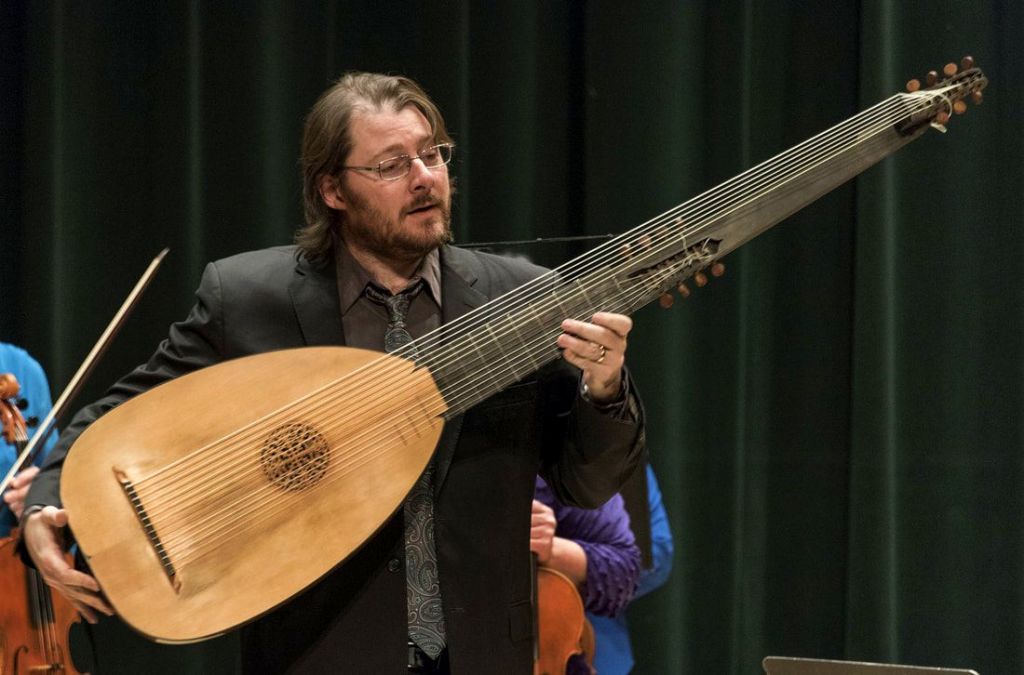 Man plays a very large lute.